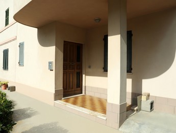 Photo of Beautiful beige building with wooden entrance door on sunny day