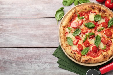 Photo of Delicious Margherita pizza and cutter on wooden table, flat lay. Space for text