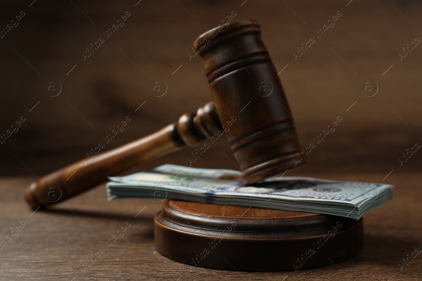 Photo of Law gavel with stack of dollars on wooden table, closeup