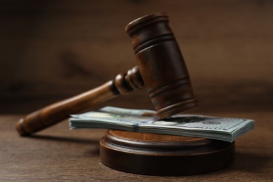 Law gavel with stack of dollars on wooden table, closeup