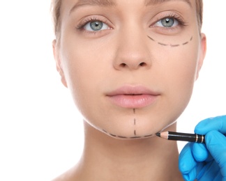 Photo of Doctor marking young woman face before cosmetic surgery on white background