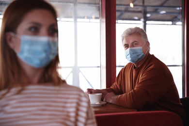 Senior man with medical mask in cafe. Virus protection