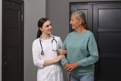 Photo of Young healthcare worker assisting senior woman indoors