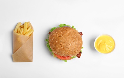 Tasty burger, french fries and sauce on white background, top view