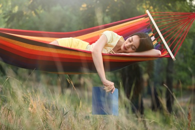 Photo of Young woman with book resting in comfortable hammock at green garden