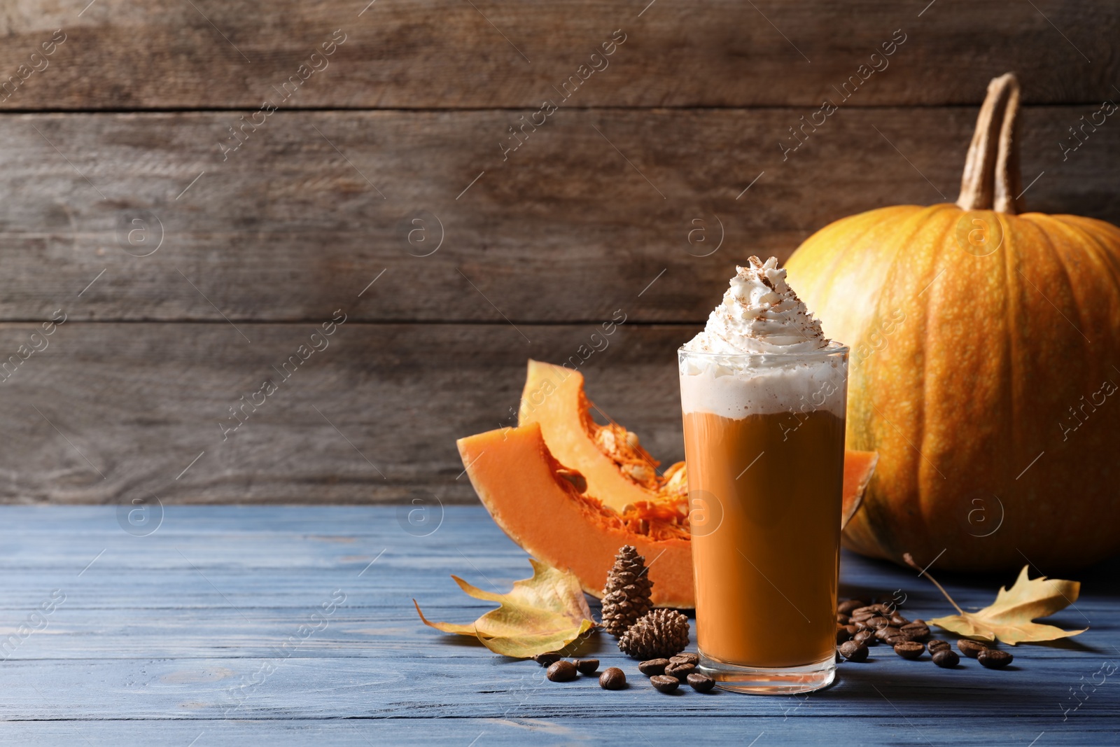 Photo of Glass with tasty pumpkin spice latte on wooden table. Space for text