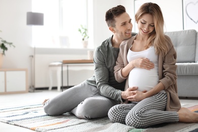 Photo of Young pregnant woman with her husband at home