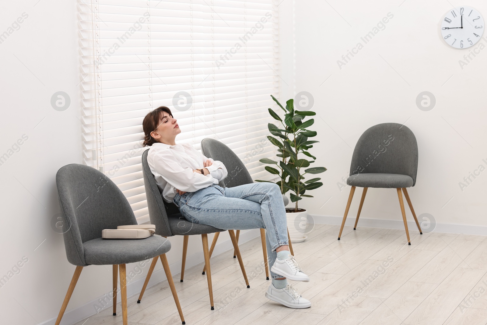 Photo of Tired woman sitting on chair and waiting for appointment indoors