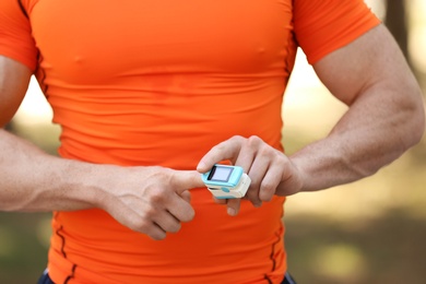 Young man checking pulse after workout, focus on hands