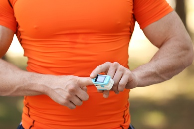 Photo of Young man checking pulse after workout, focus on hands