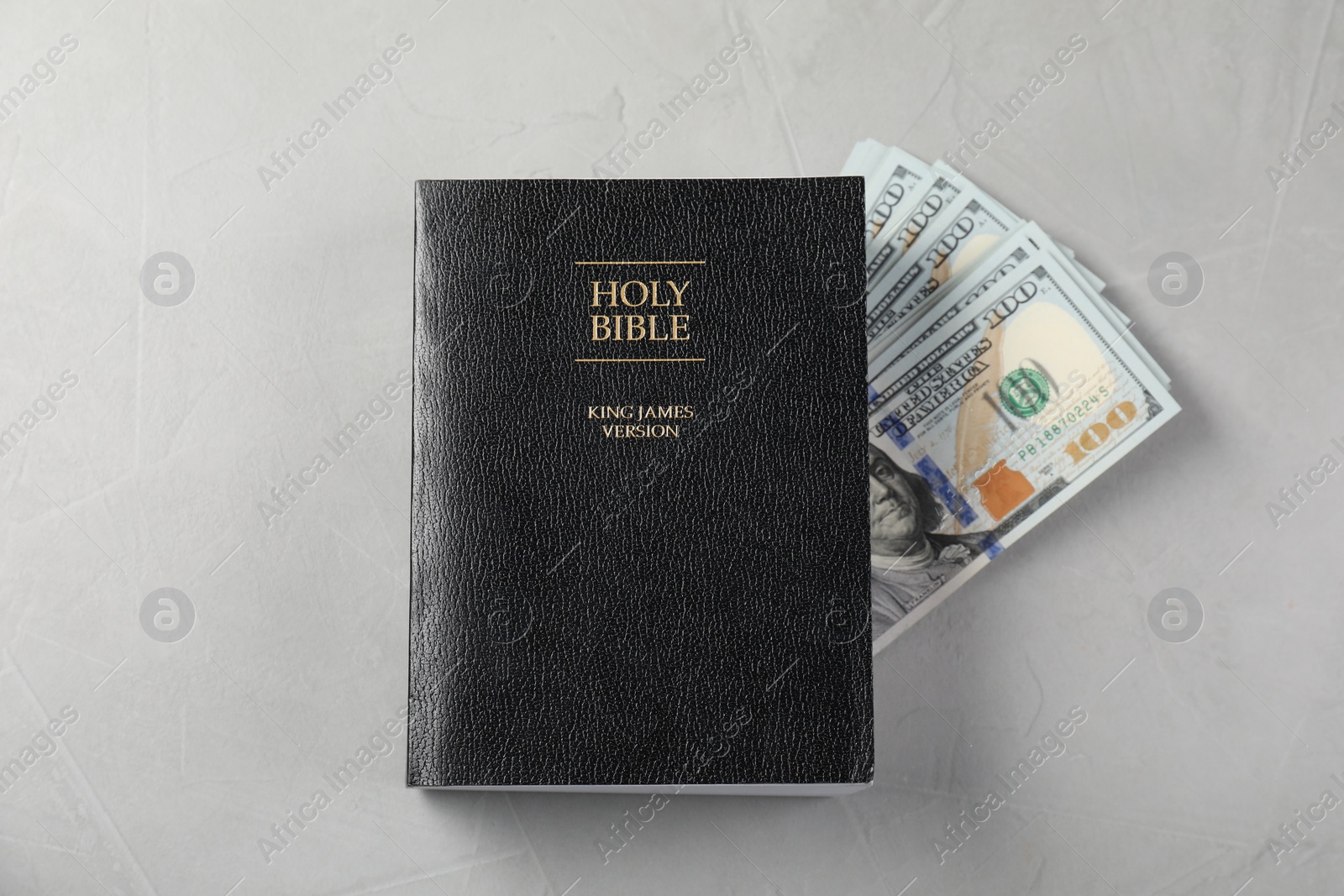 Photo of Holy Bible and money on grey table, top view