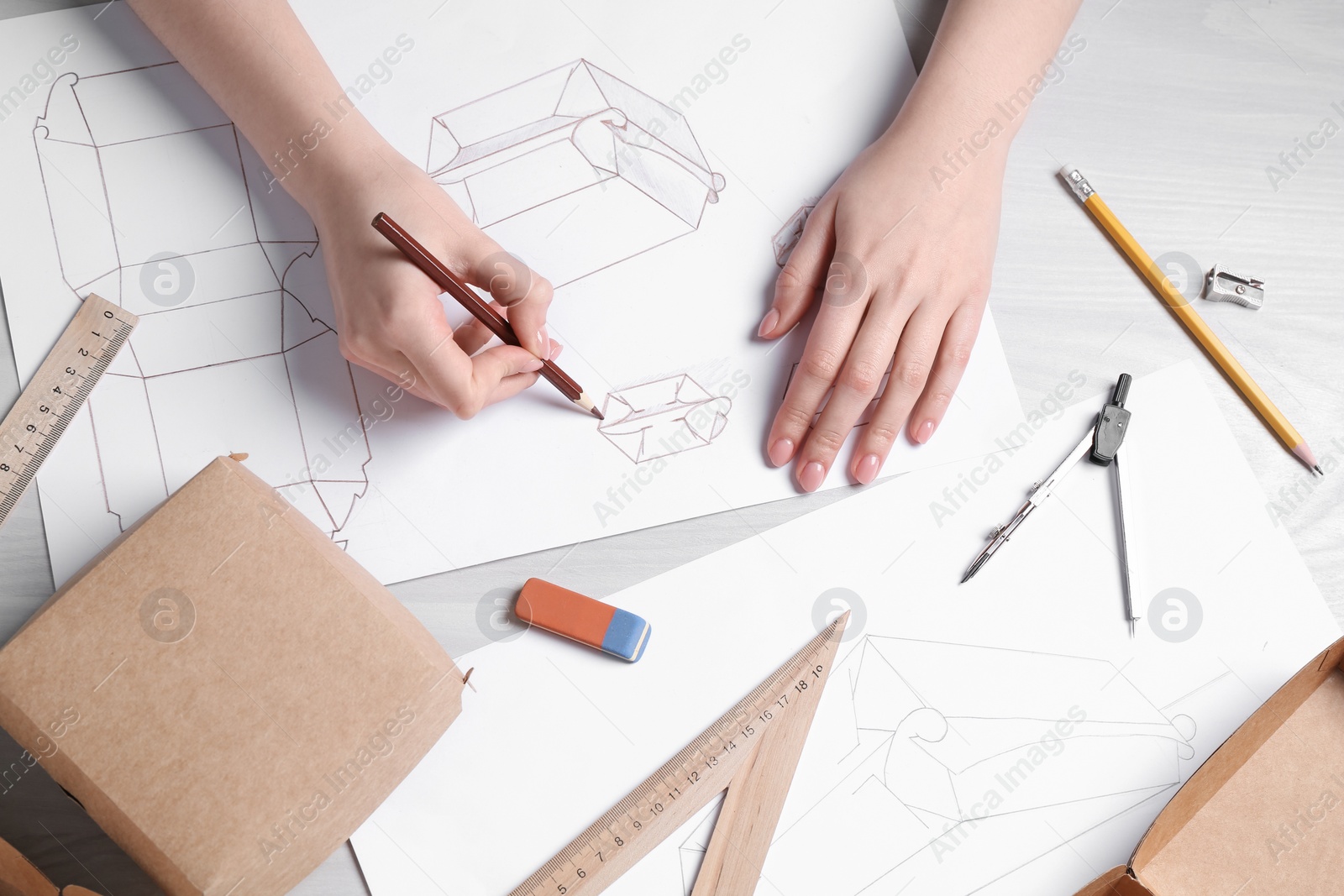 Photo of Woman creating packaging design at light wooden table, top view