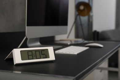 Photo of Electronic clock near computer on table indoors, space for text. Interior element