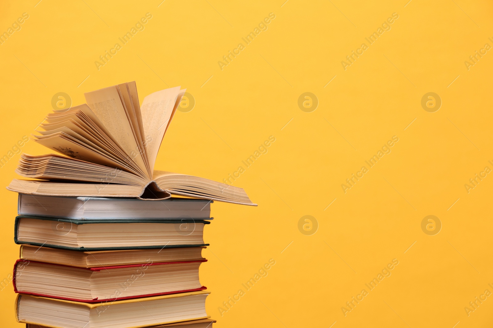 Photo of Many hardcover books on orange background, space for text. Library material