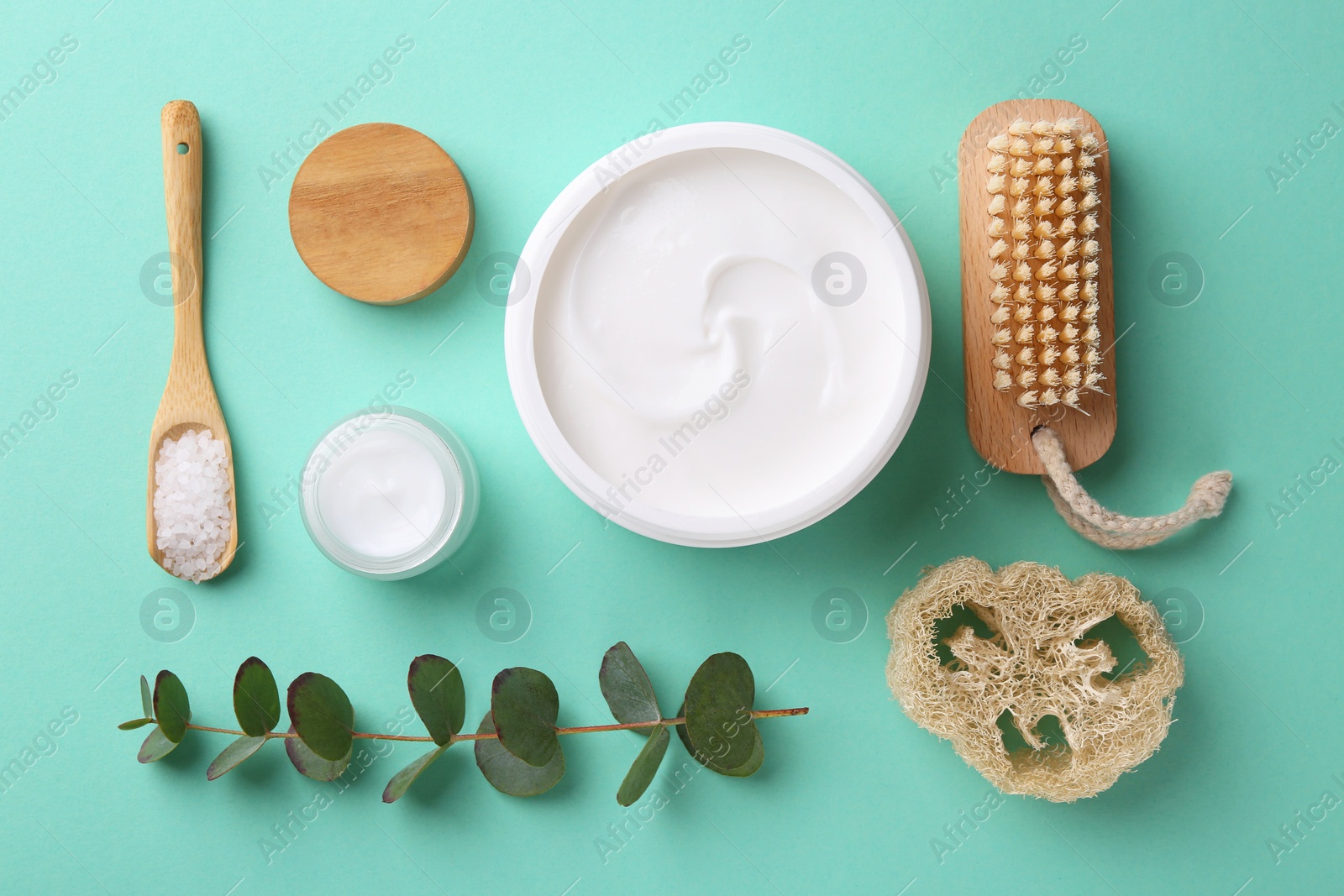 Photo of Jars of cream, body care products and eucalyptus branch on turquoise background, flat lay