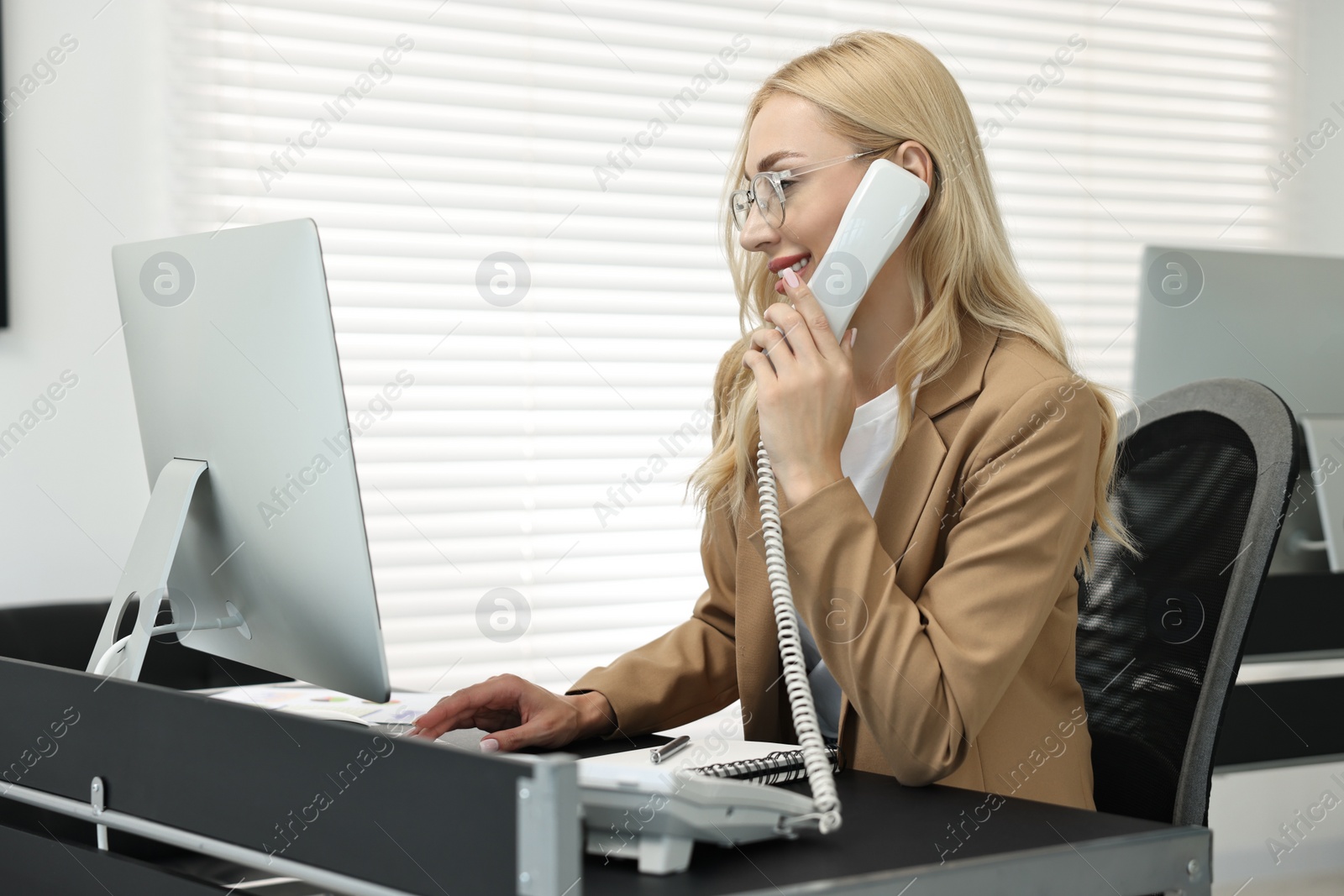 Photo of Secretary talking on phone at table in office