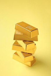 Stack of shiny gold bars on yellow background