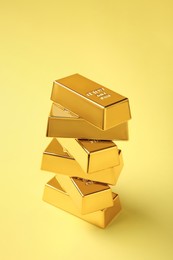 Photo of Stack of shiny gold bars on yellow background