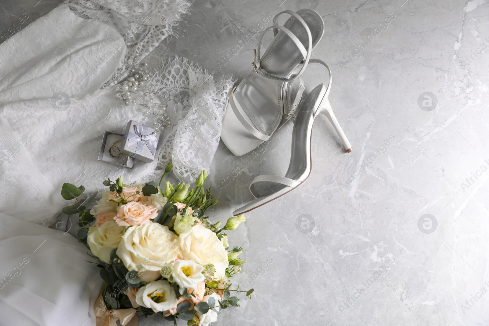 Photo of Flat lay composition with white wedding dress and bouquet on grey marble table. Space for text