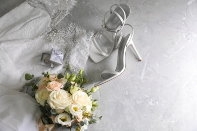 Photo of Flat lay composition with white wedding dress and bouquet on grey marble table. Space for text