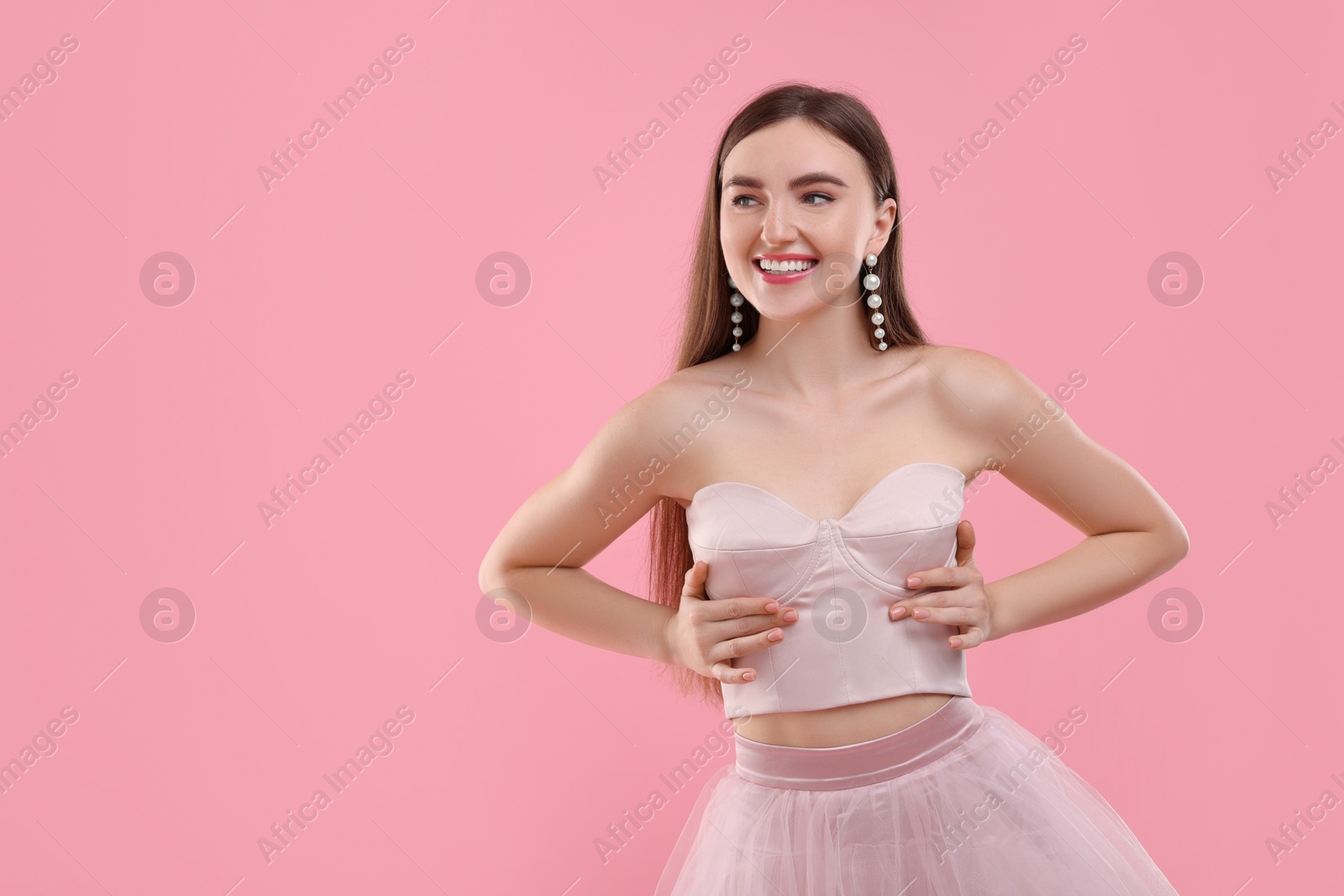 Photo of Beautiful woman in pale pink clothes on color background, space for text
