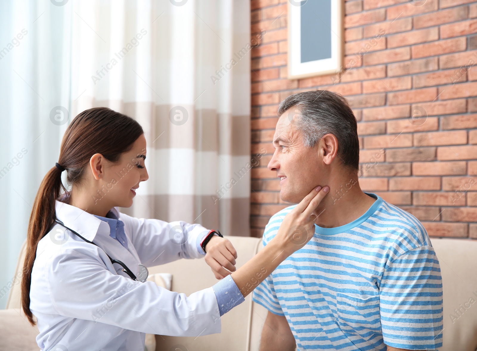 Photo of Doctor checking mature man's pulse with fingers at home