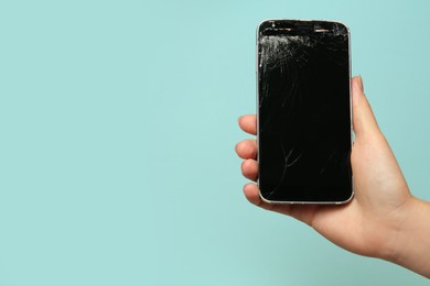 Photo of Woman holding damaged smartphone on light blue background, closeup with space for text. Device repairing