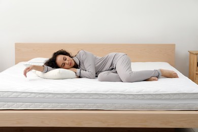 Photo of Young African American woman sleeping on bed with comfortable mattress and pillow at home