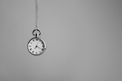 Stylish pendulum on light grey background, space for text. Hypnotherapy session