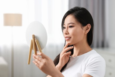 Woman with perfect skin looking at mirror indoors