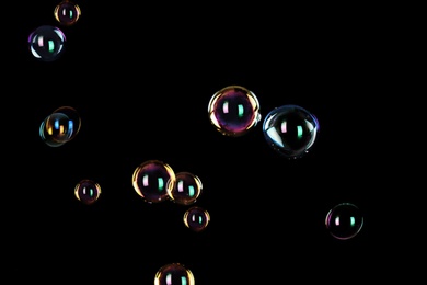 Photo of Beautiful translucent soap bubbles on dark background