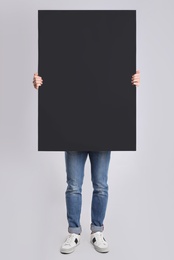 Photo of Man holding blank poster on light grey background