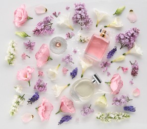 Luxury perfumes and floral decor on white background, flat lay