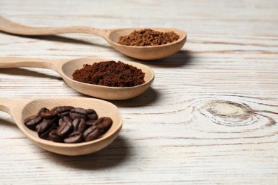 Photo of Spoons with instant, ground coffee and roasted beans on white wooden table, closeup