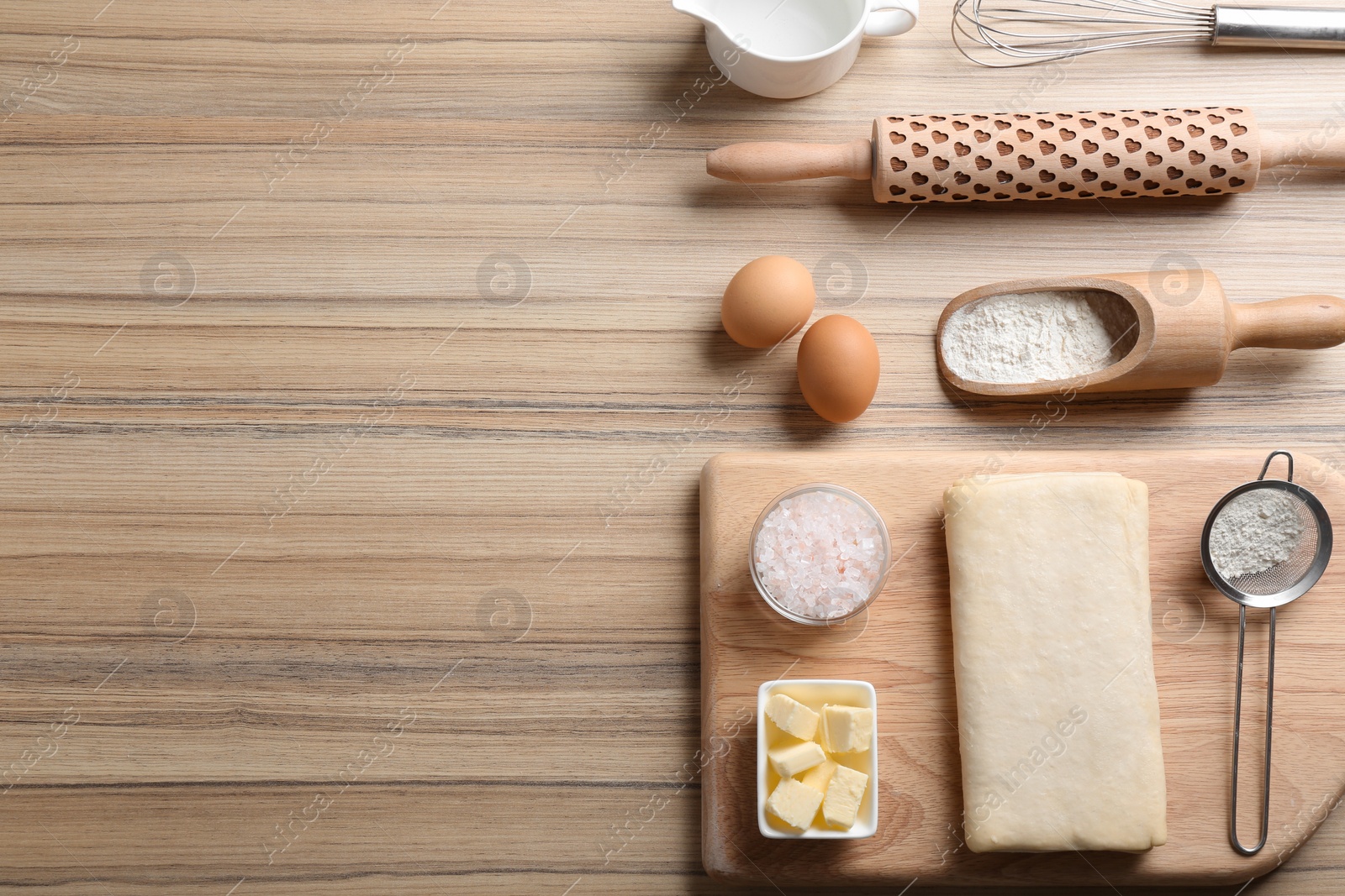 Photo of Puff pastry dough and ingredients on wooden table, flat lay. Space for text