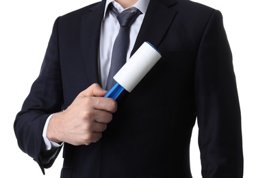 Young man cleaning jacket with lint roller on white background