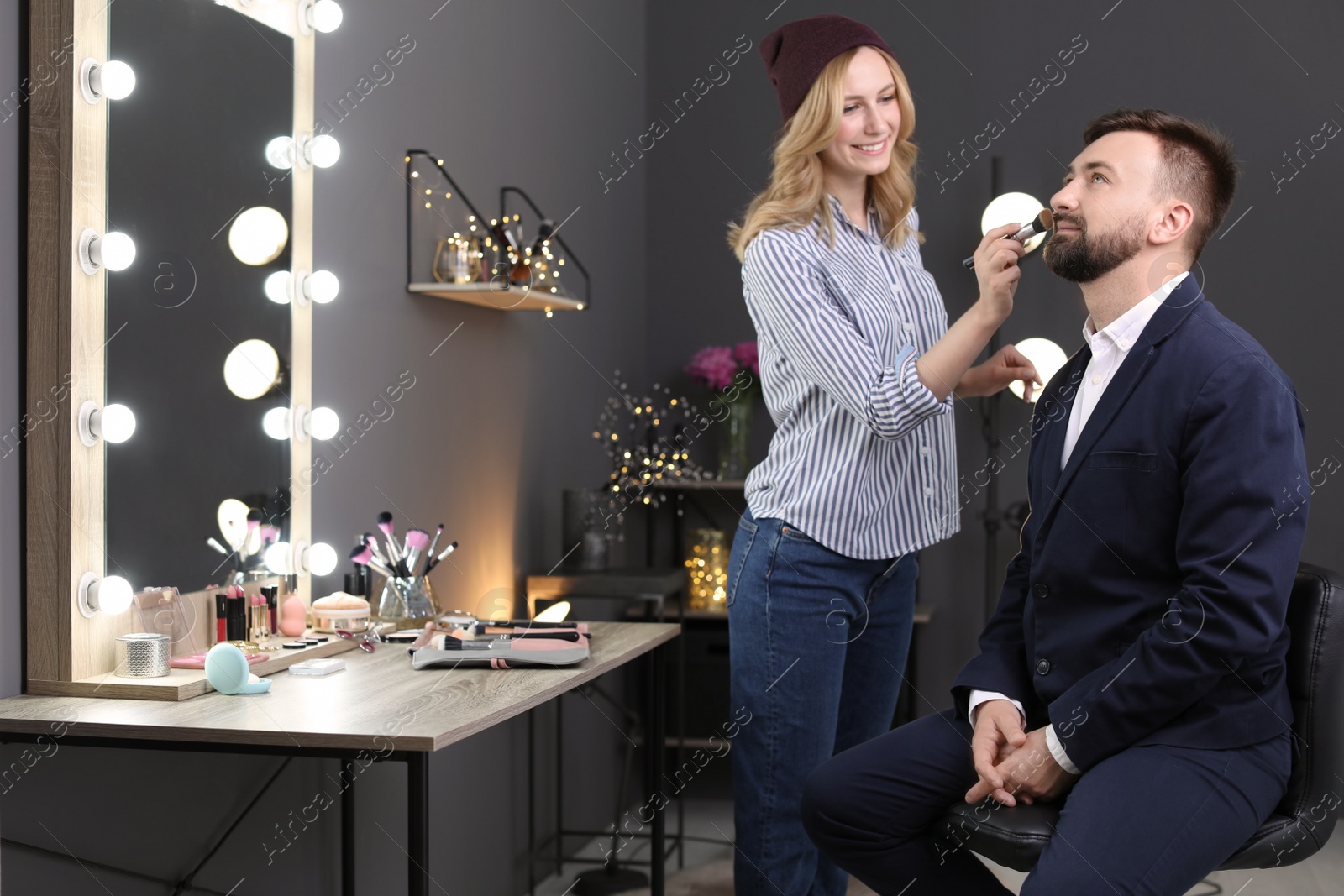 Photo of Professional makeup artist working with client in dressing room