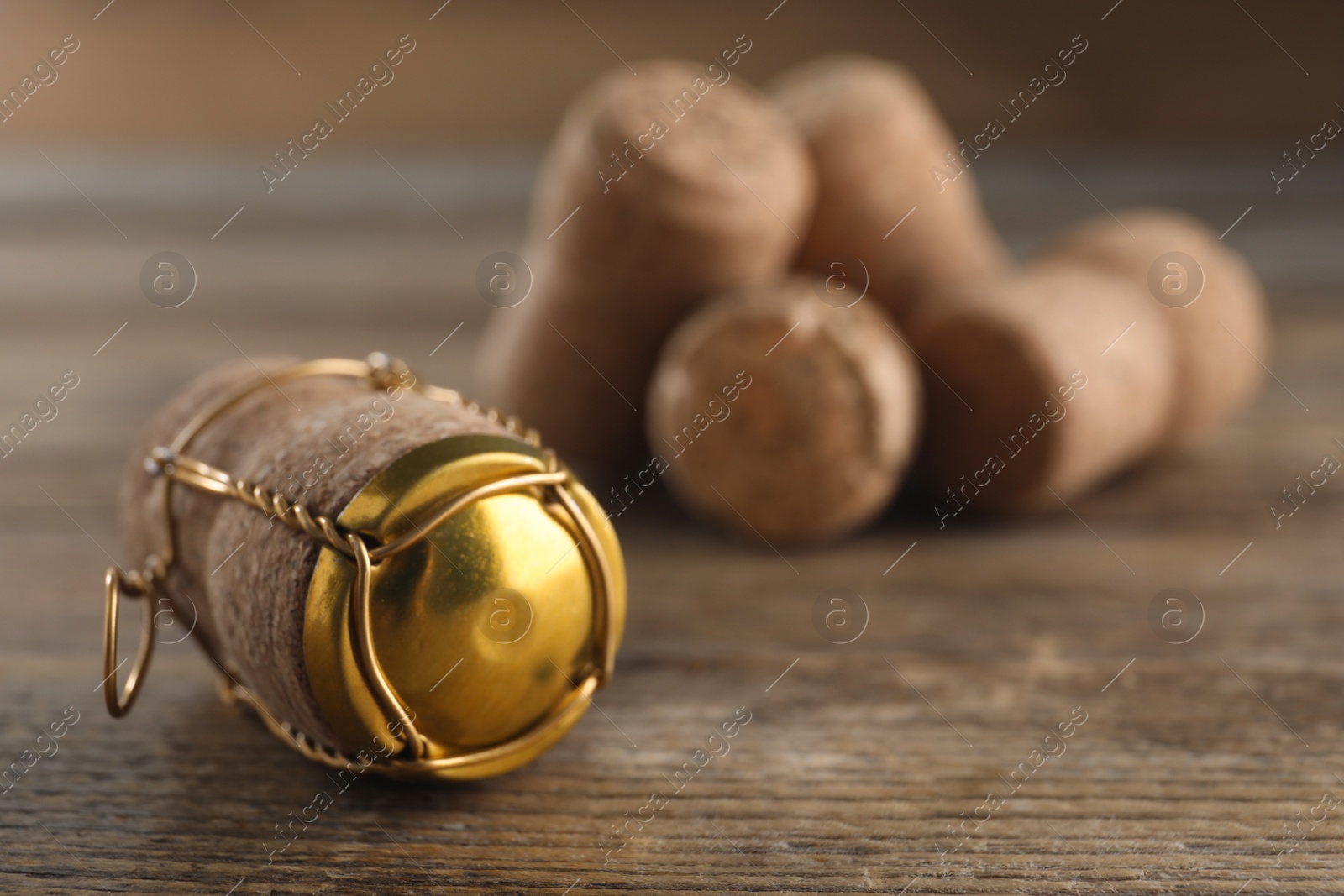 Photo of Cork of sparkling wine and muselet cap on wooden table, closeup. Space for text