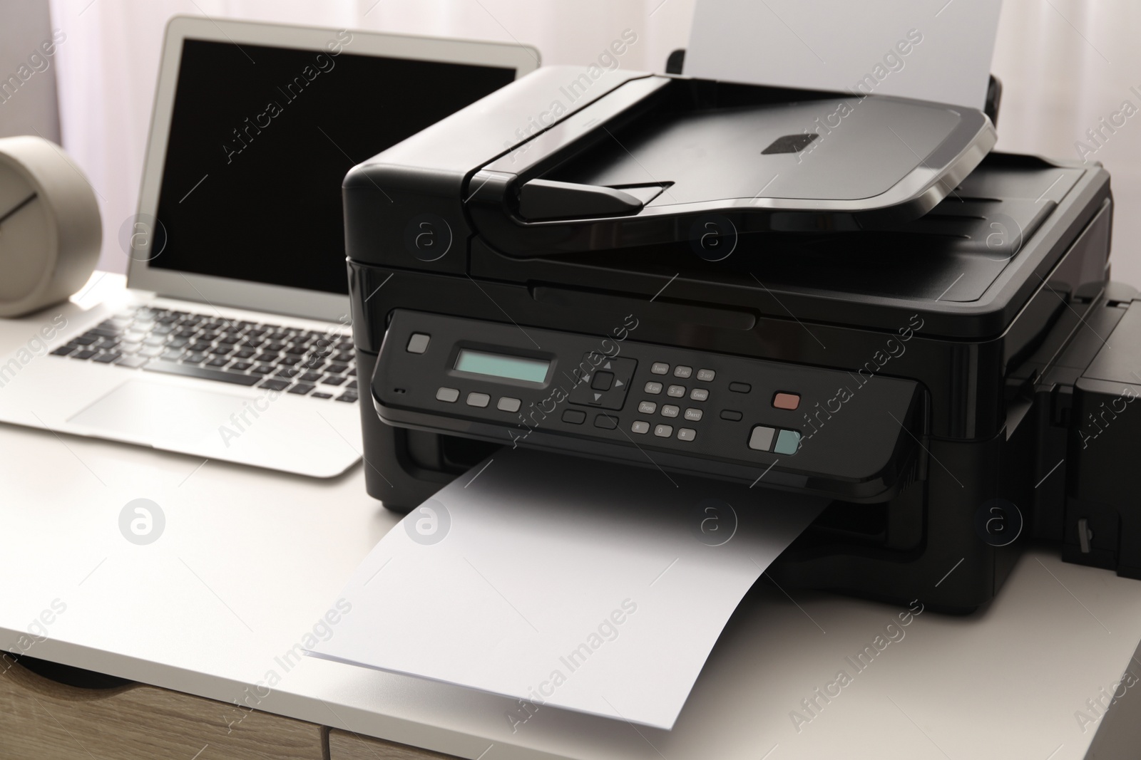 Photo of Modern printer and laptop on white table indoors