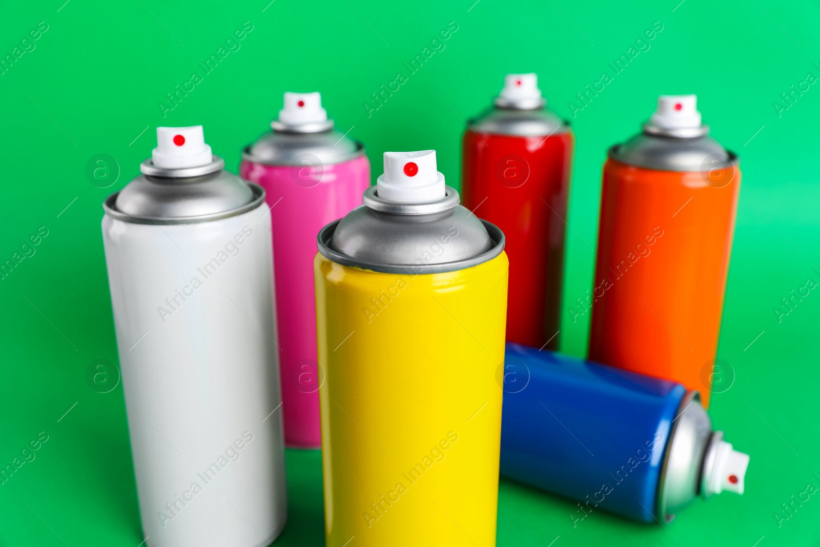 Photo of Colorful cans of spray paints on green background