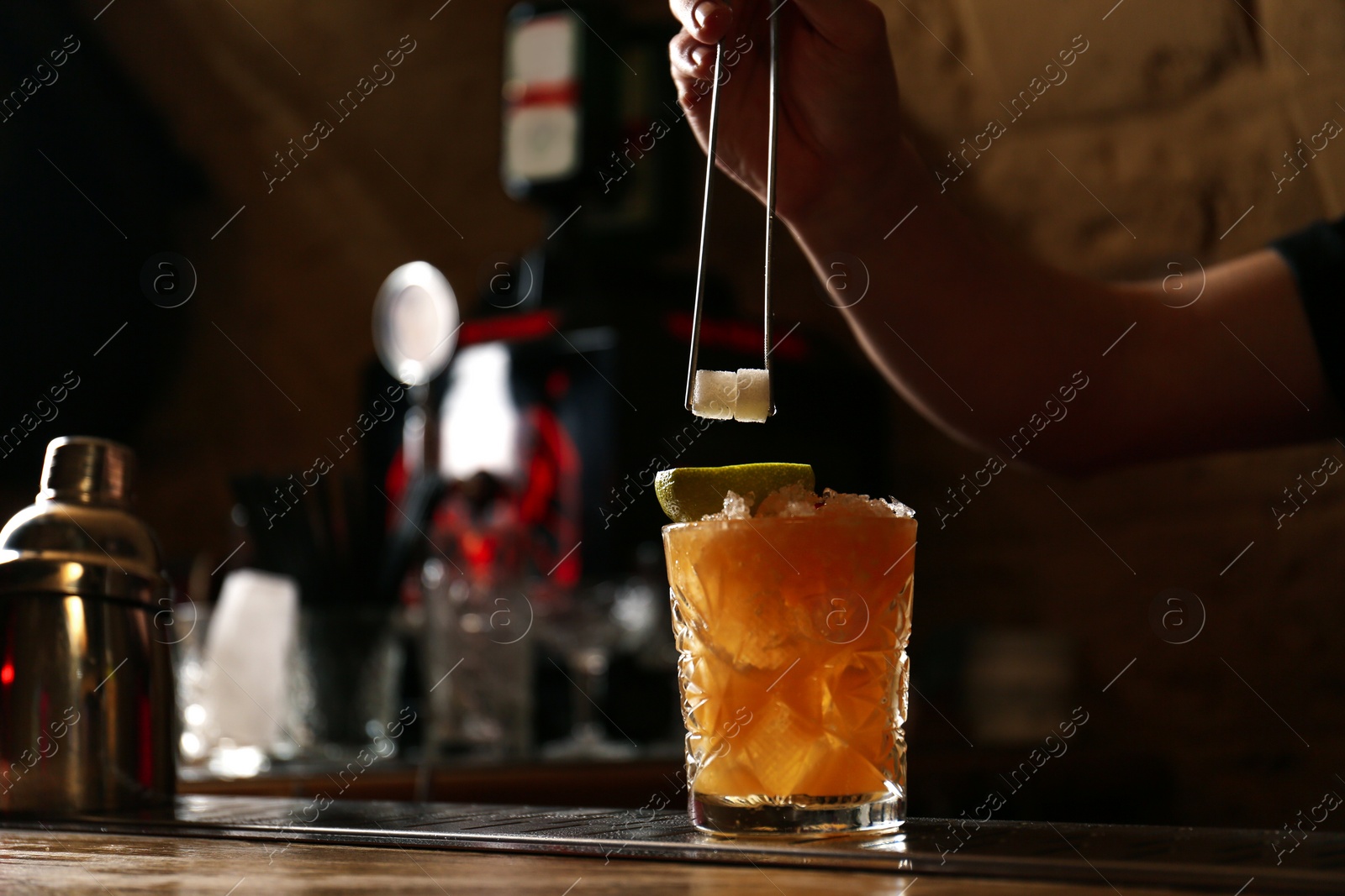 Photo of Bartender decorating glass of fresh alcoholic cocktail at bar counter, closeup. Space for text