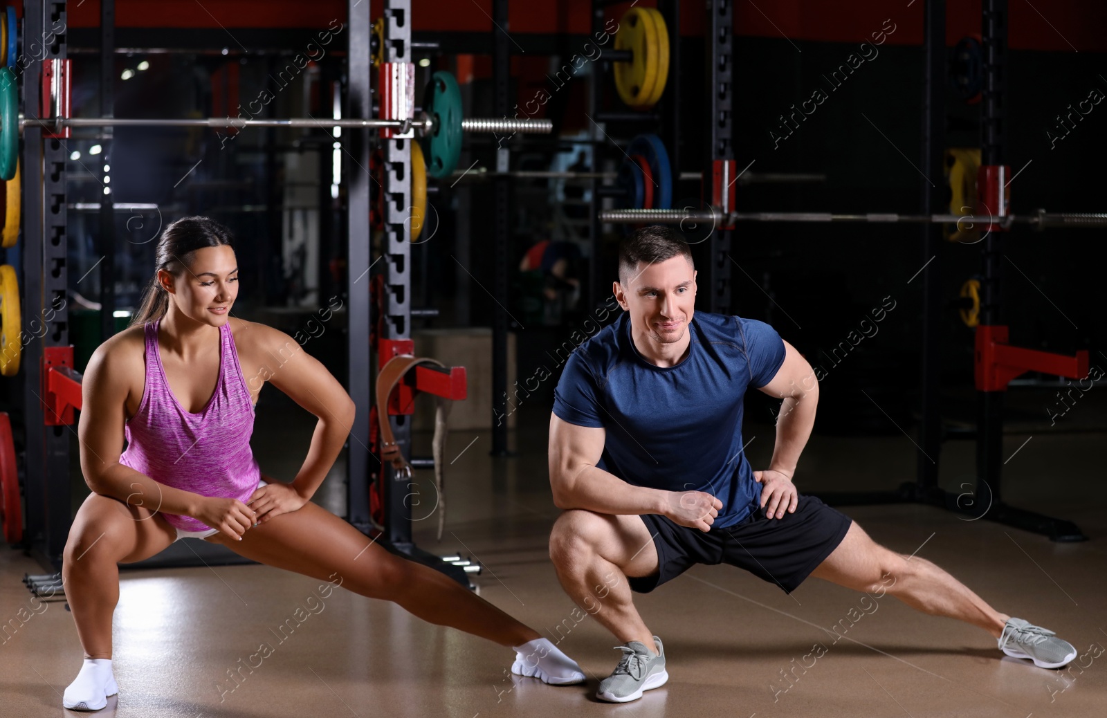 Photo of Couple stretching after workout in modern gym