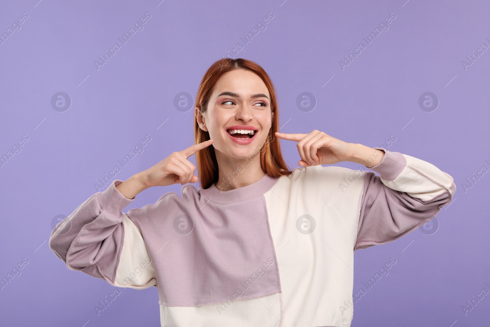 Photo of Beautiful woman showing her clean teeth and smiling on violet background