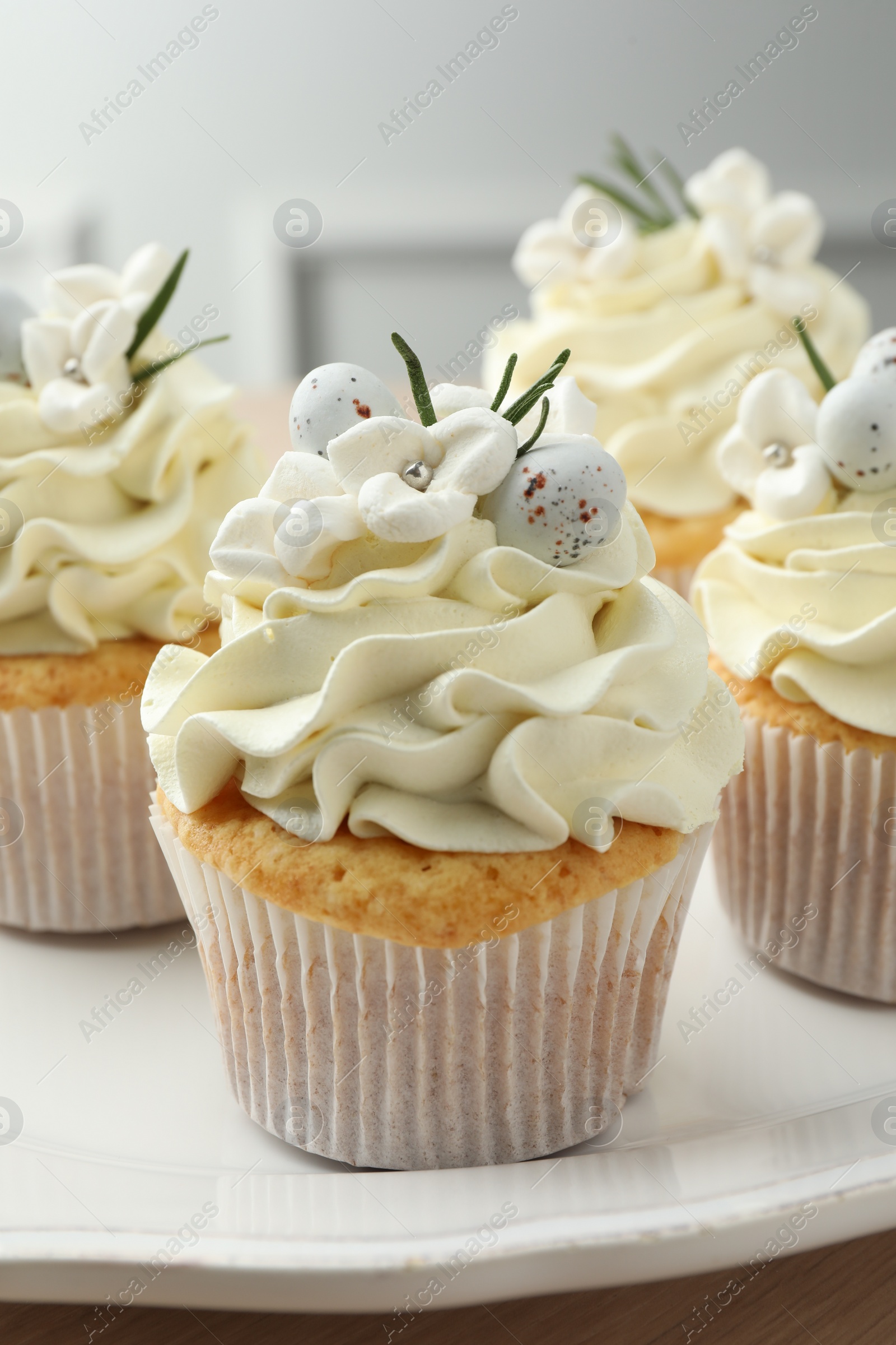 Photo of Tasty Easter cupcakes with vanilla cream on table, closeup