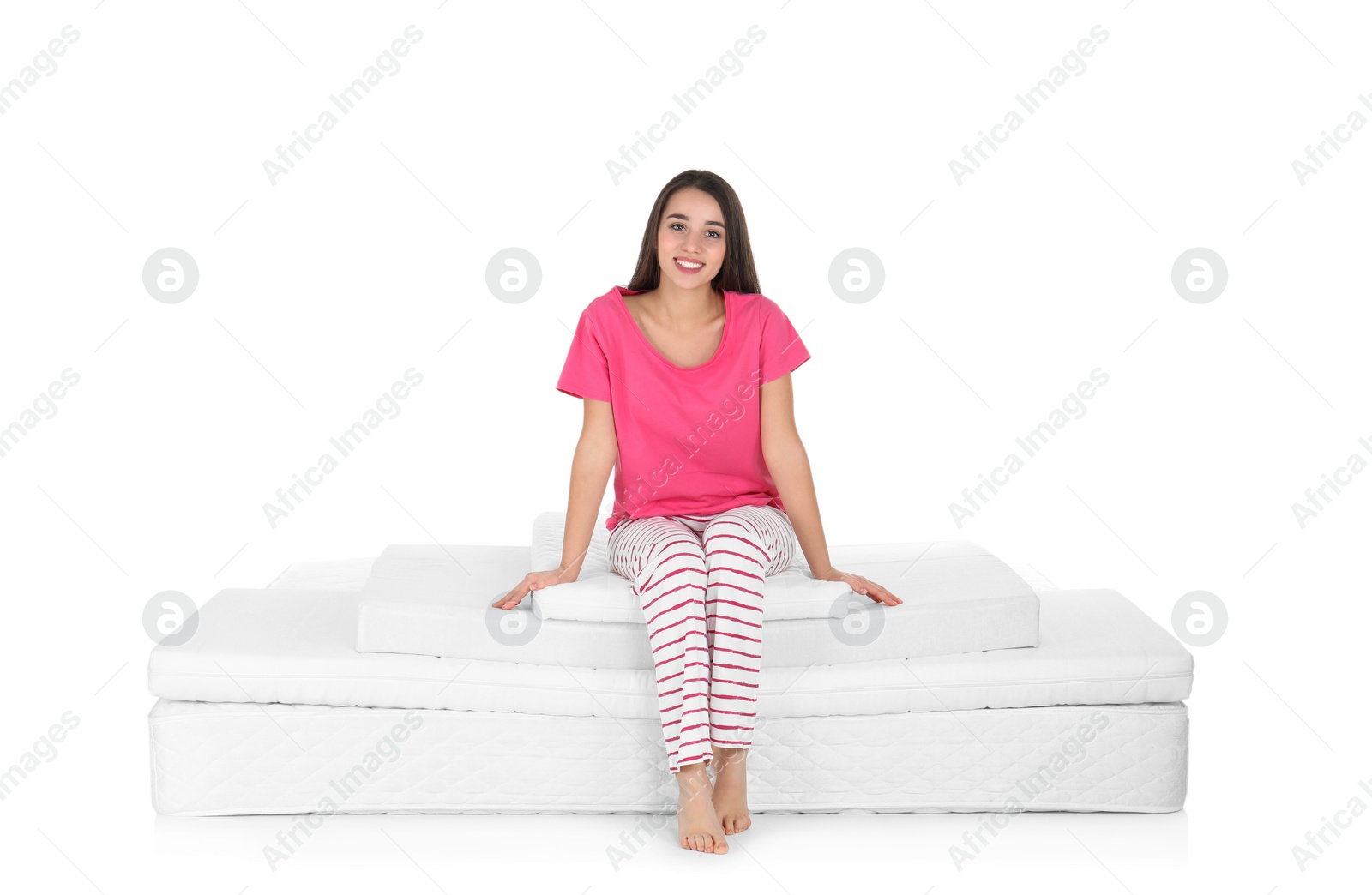 Photo of Young woman sitting on mattress pile against white background