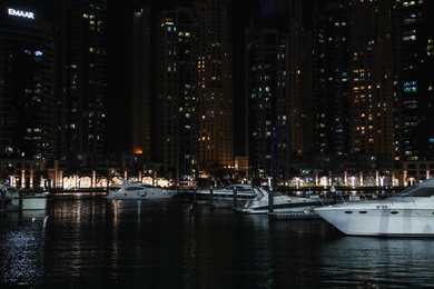Photo of DUBAI, UNITED ARAB EMIRATES - NOVEMBER 03, 2018: Night cityscape with luxury yachts moored at pier