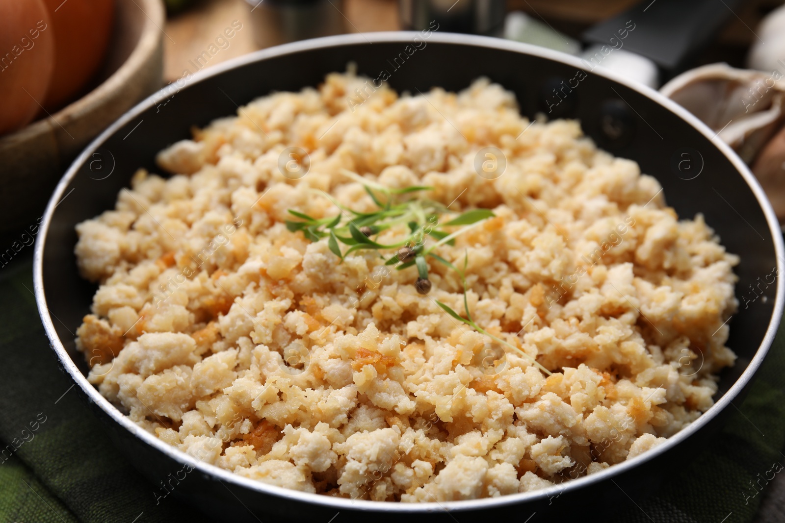 Photo of Fried ground meat in frying pan and microgreens on table, closeup