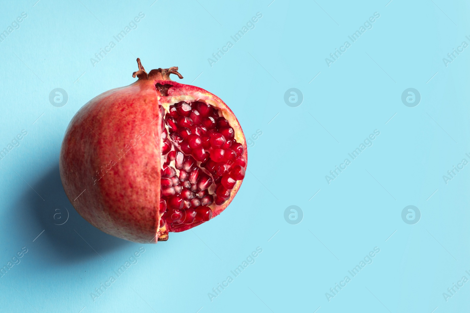 Photo of Ripe pomegranate on color background, top view with space for text