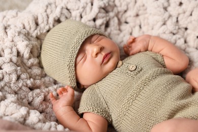 Cute newborn baby sleeping on white knitted plaid, closeup