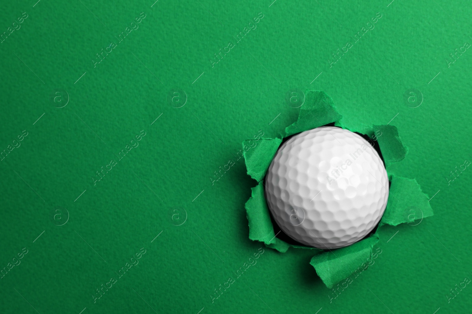 Photo of Torn color paper with golf ball, space for text. Sport equipment